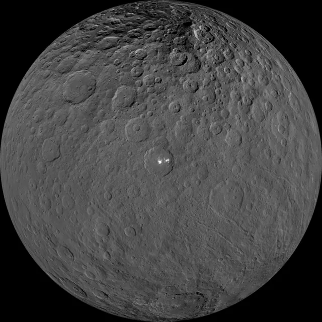 Ceres, a round grey world full of craters, with a bright spot in Occator crater, photographed by the Dawn spacecraft