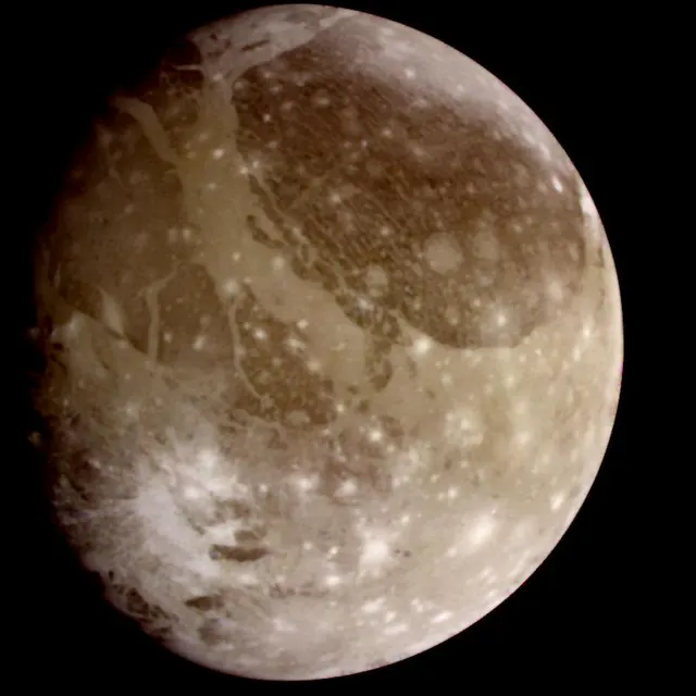 Ganymede in colour, with dark and bright regions crossed by grooves, photographed by the Galileo spacecraft