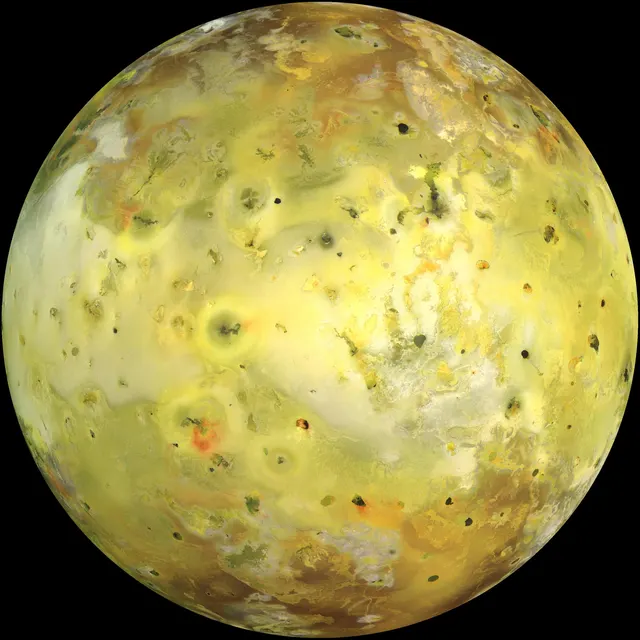 Ío en color real, amarilla y anaranjada por el azufre y salpicada de manchas oscuras de volcanes, fotografiada por la sonda Galileo