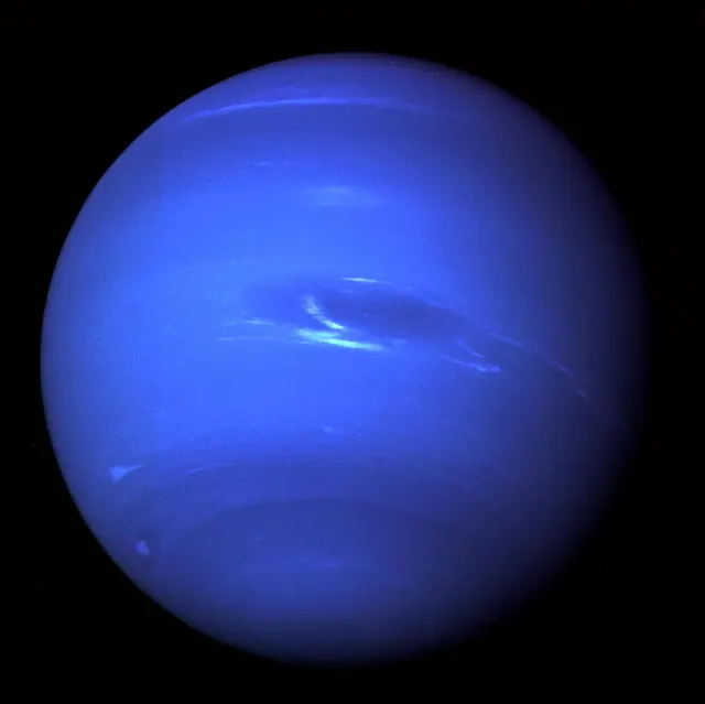 Neptune, deep blue with white clouds and dark spots, photographed by Voyager 2