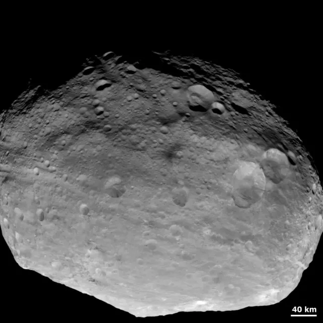 The asteroid Vesta, grey, irregular and covered in craters, photographed by the Dawn spacecraft